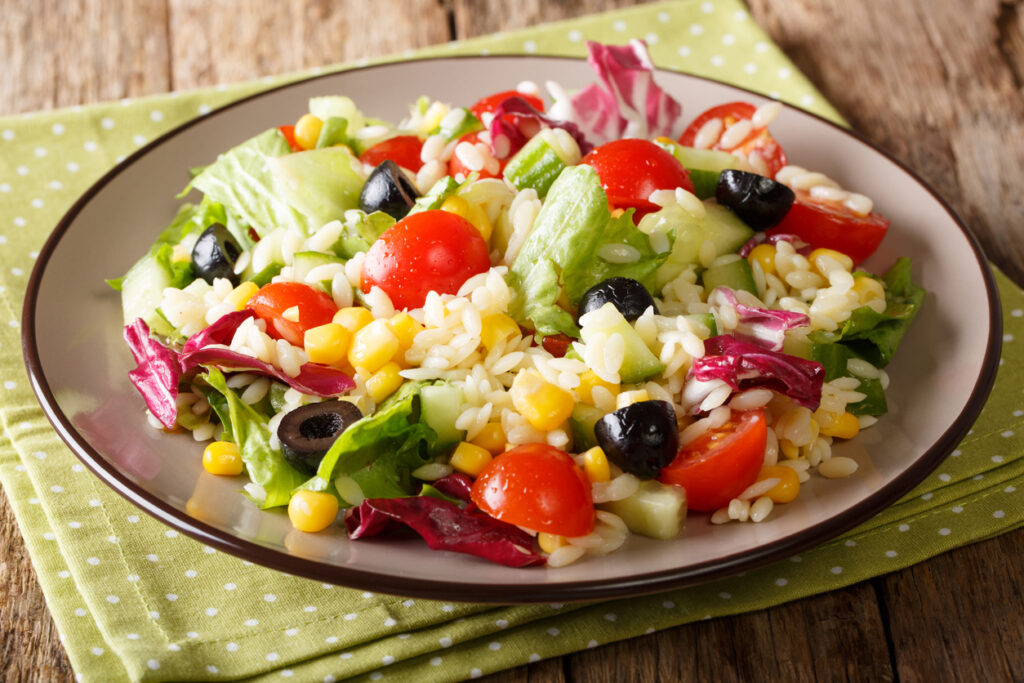 A plate of salad with corn, tomatoes and lettuce.